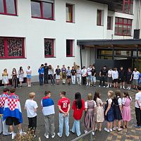Schüler versammeln sich zu einer Veranstaltung in einem Innenhof vor einem Schulgebäude.