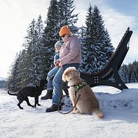 Winterwandern mit Hund im Wildmoos_zwei Frauen mit Hunden sitzen auf Holzliege bei Ferienheim-Lichtung